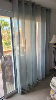 teal/green eyelet curtains hanging at window in Alfaz del Pi